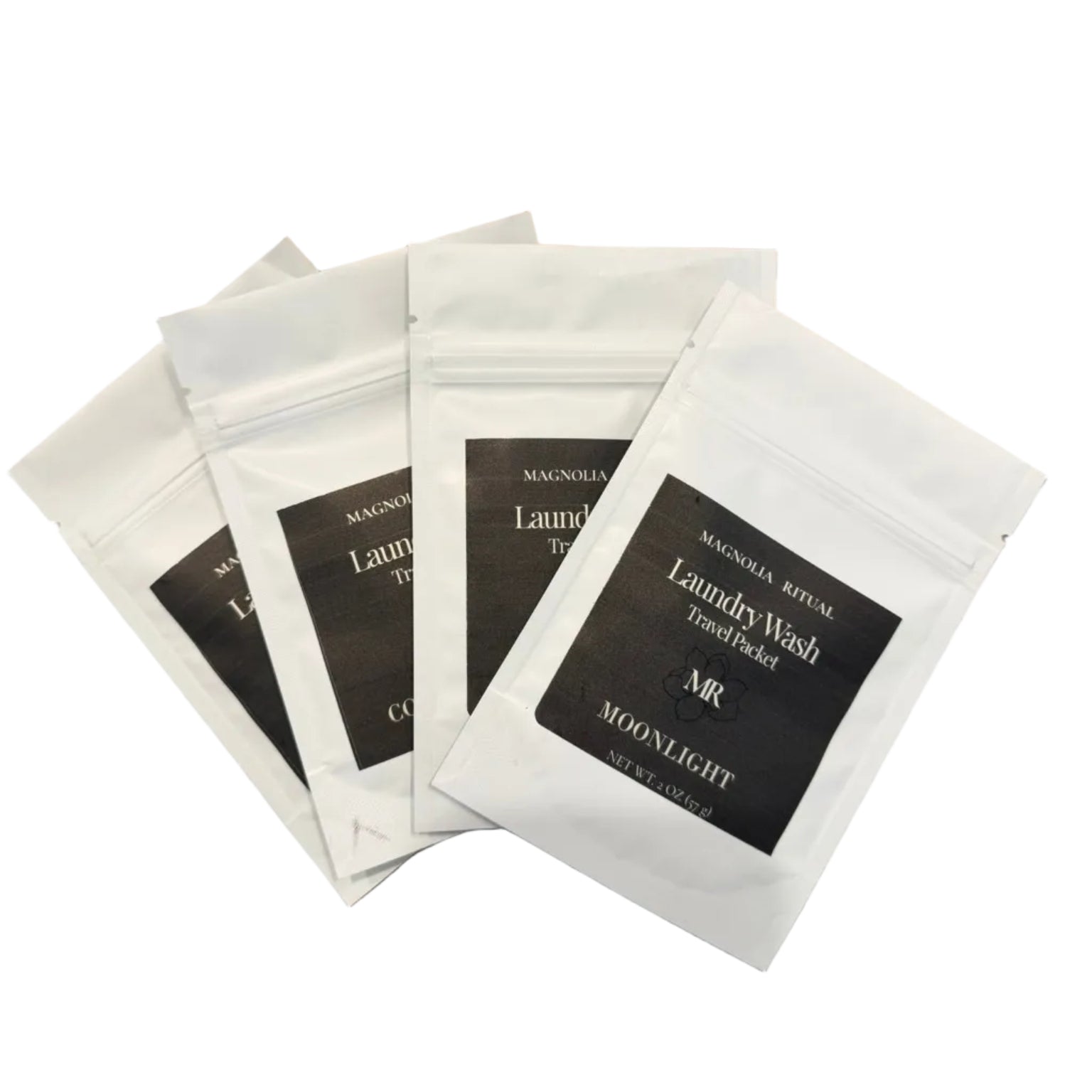 Four white stand-up pouches of Magnolia Natural Laundry Wash Toned Picked Moonlight scent arranged in a fan on a brown wooden surface.